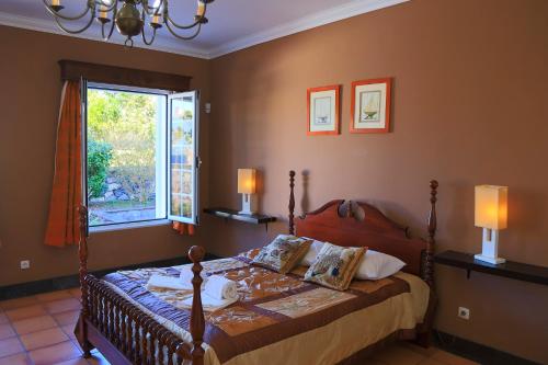 a bedroom with a bed with two lamps and a window at Bella Italia Populo Guest House in Ponta Delgada
