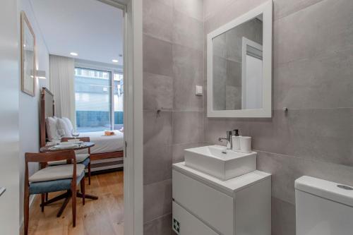 ein Bad mit einem Waschbecken und einem Spiegel sowie ein Schlafzimmer in der Unterkunft Cozy Studio w/ Patio by LovelyStay in Porto