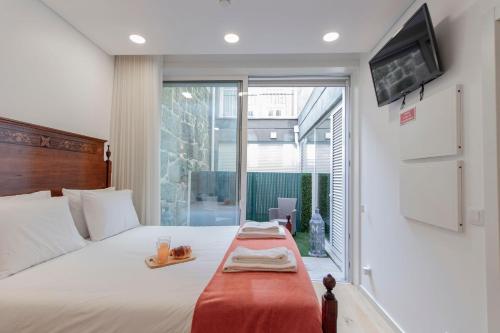 ein Schlafzimmer mit einem großen Bett und einem TV an der Wand in der Unterkunft Cozy Studio w/ Patio by LovelyStay in Porto