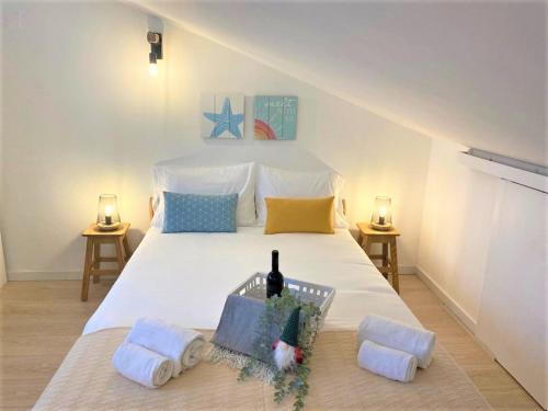 een slaapkamer met een wit bed en een fles wijn erop bij Sinos da Sé in Setúbal