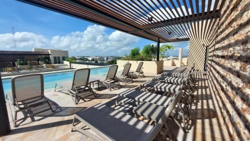 eine Gruppe von Stühlen auf einer Terrasse mit einem Pool in der Unterkunft Syrena Luxury Caribbean in Playa del Carmen