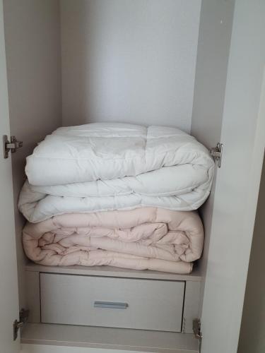 two blankets are stacked on a shelf in a closet at Cozy House in Daegu