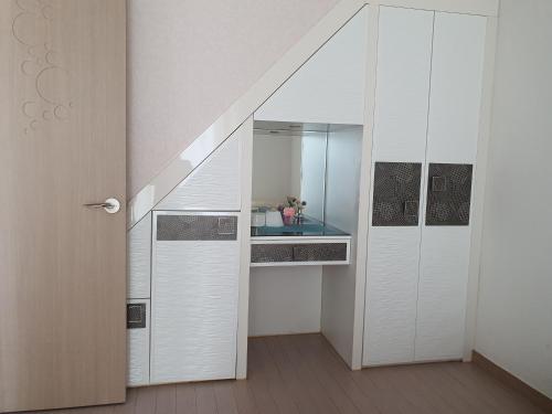 a room with a staircase with white cabinets and a mirror at Cozy House in Daegu