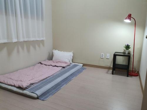 a bed in a room with a pink blanket on the floor at Cozy House in Daegu