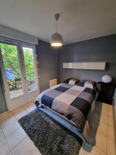 una camera da letto con un letto con un tappeto e due finestre di Le Rethel a Caen