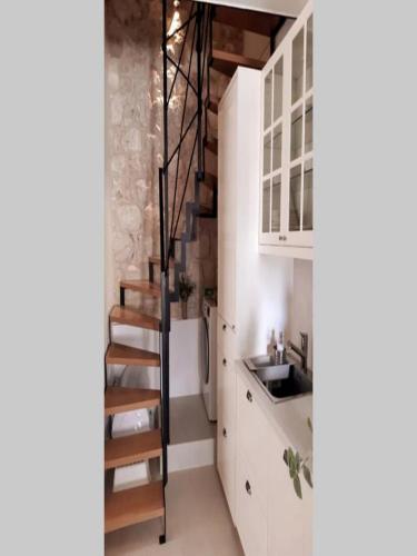 a kitchen with a spiral staircase in a small room at Casa Ruben, private stone house in Vis