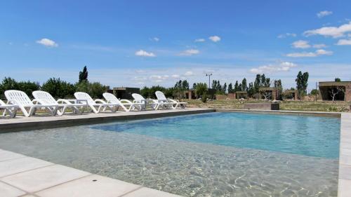 a group of white chairs sitting next to a swimming pool at Complejo Turístico Chachingo in Maipú