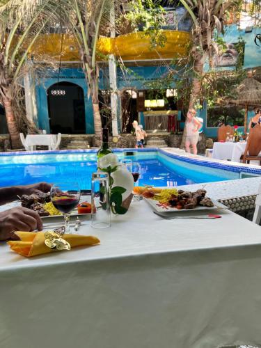 a table with a plate of food next to a swimming pool at Maison du Bonheur in Dakar