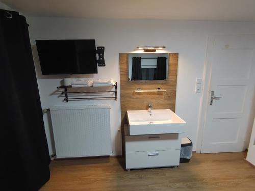 uma casa de banho com um lavatório e uma televisão na parede em Loisachtalerhof em Grainau