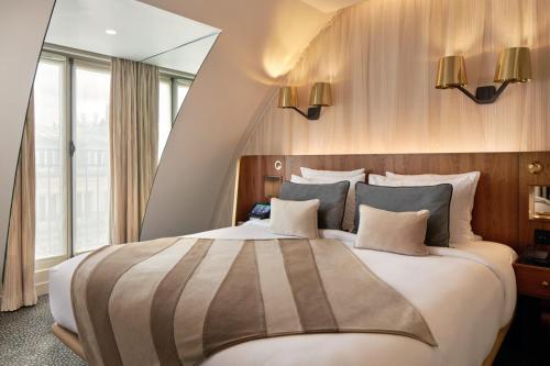 a large bed in a room with a large window at Maison Albar - Le Pont-Neuf in Paris