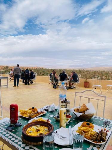 a table with food on top of a roof at Hotel Kasbah Ennakhile in Nkob