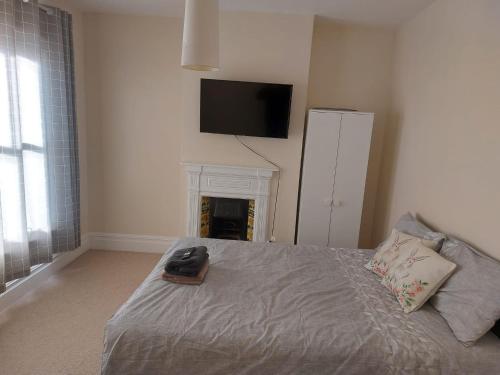 a bedroom with a bed with a fireplace and a tv on the wall at Rooms In A Victorian Comfortable 4-bedroom house in Milton Keynes Rooms Not En-suites in Wolverton