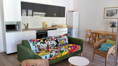 salon z zieloną kanapą i kuchnią w obiekcie Le Mas de la Palmeraie - Appartement dans propriété privée au calme avec piscine et tennis w mieście Bormes-les-Mimosas