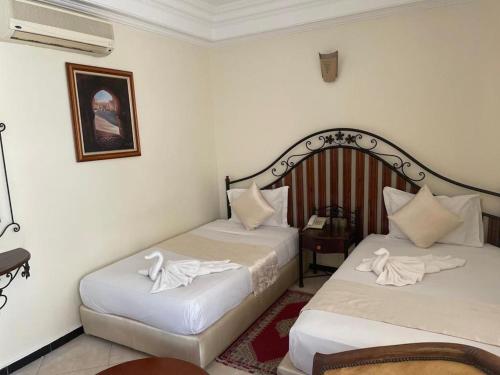 two beds in a room with white sheets at Perla Hôtel in Fès