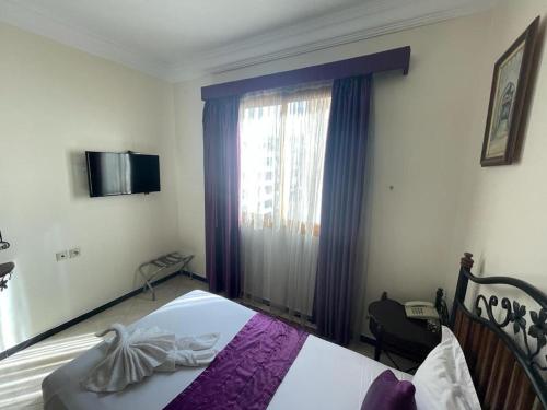 a bedroom with a bed with purple curtains and a window at Perla Hôtel in Fès