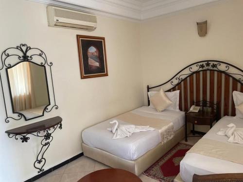 a hotel room with two beds and a mirror at Perla Hôtel in Fès
