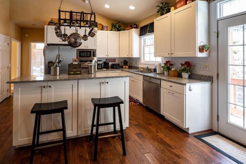 a kitchen with white cabinets and two bar stools at stayNantahala - Smoky Mountain Cabins in Aquone