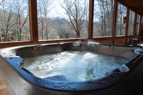 a large bath tub in a room with a window at stayNantahala - Smoky Mountain Cabins in Aquone