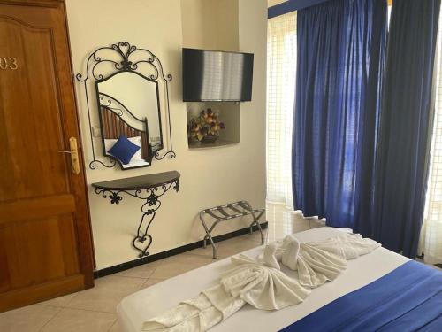 a bedroom with a bed with a mirror and blue curtains at Perla Hôtel in Fès