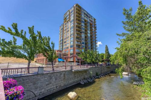 a tall building next to a river in a city at Panorama Place in Reno