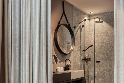 a bathroom with a shower and a sink and a mirror at Nomad by CERVO Mountain Resort in Zermatt