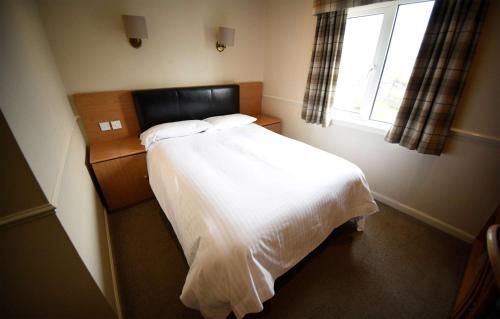 a bedroom with a white bed and a window at The Caledonian in Portree