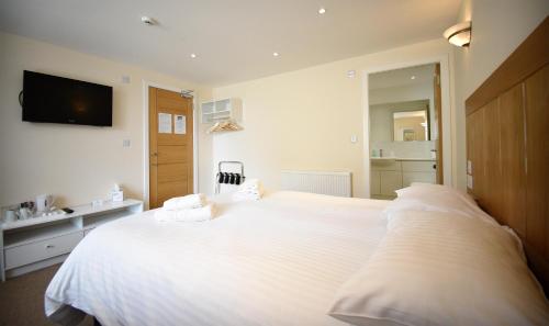 um quarto com uma grande cama branca e 2 almofadas em The Caledonian em Portree