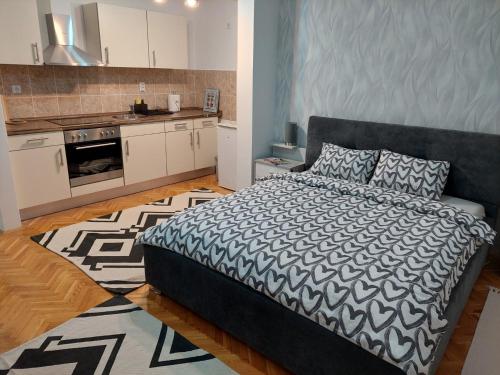 a bedroom with a bed and a kitchen at Apartman Bart in Subotica