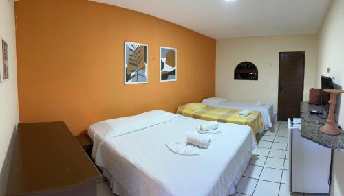 a hotel room with two beds and a television at Pousada Enseada do Sol in Jacumã