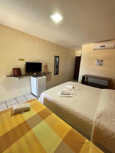 a hotel room with two beds and a television at Pousada Enseada do Sol in Jacumã