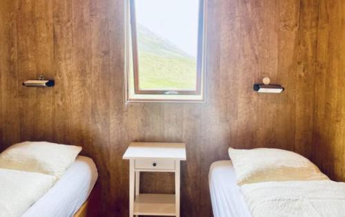 a small room with two beds and a window at Hidden Cottages in Kvíabekkur