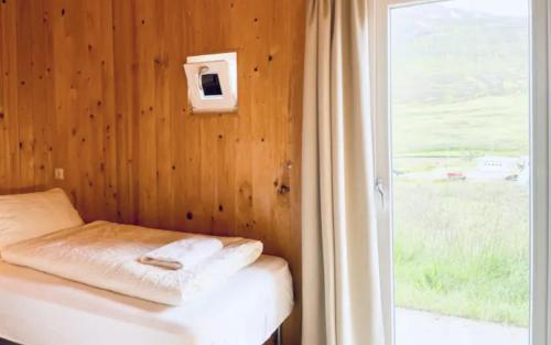 a room with a bed with a window and a curtain at Hidden Cottages in Kvíabekkur