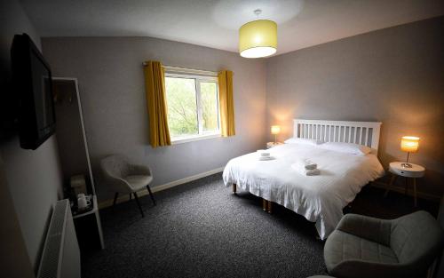 a bedroom with a white bed and a window at The Caledonian in Portree