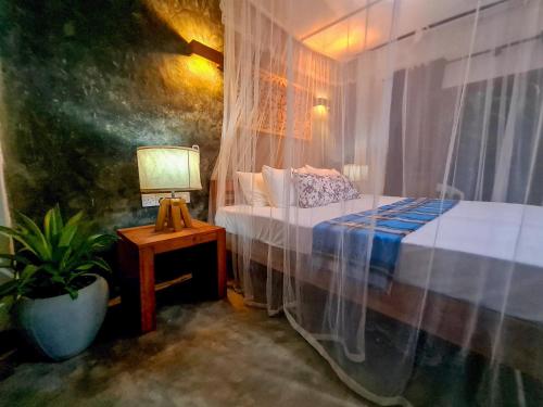 - une chambre avec un lit et une table avec une lampe dans l'établissement sahasna (one bedroom private villa), à Unawatuna