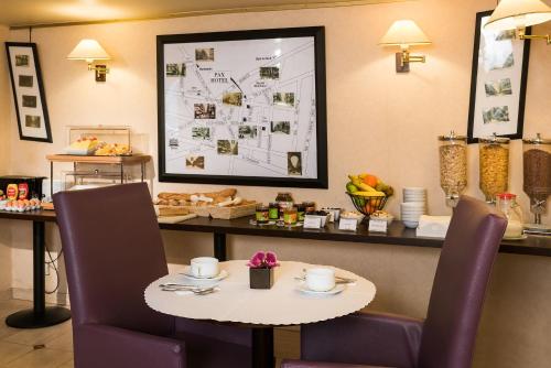 パリにあるホテル パックス オペラのテーブルと椅子、テーブル、地図付きのレストランを併設しています。