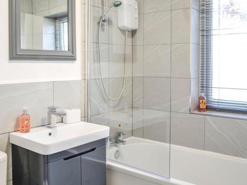a white bathroom with a sink and a shower at Bramble Cottage in Brampton