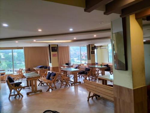 een restaurant met houten tafels, stoelen en ramen bij Hotel Karma Muzaffarabad in Muzaffarabad