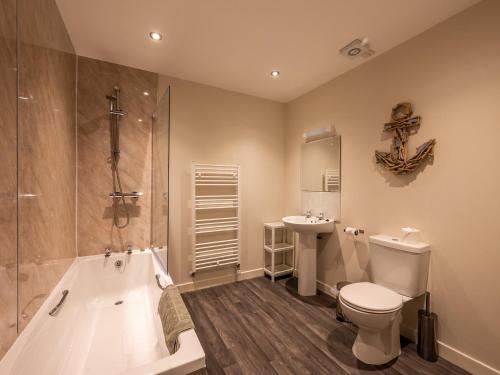 a bathroom with a tub and a toilet and a sink at The Cottage at Corriness House in Achnasheen