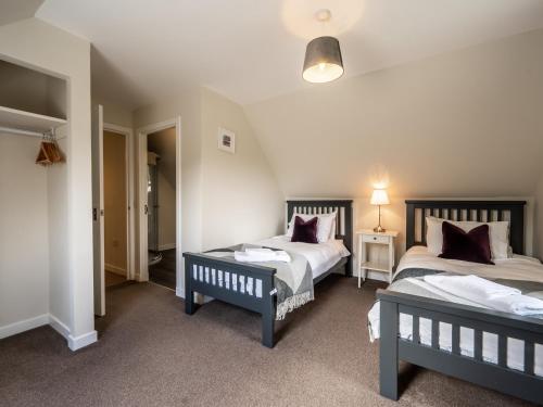 a room with two beds and two tables in it at The Cottage at Corriness House in Achnasheen