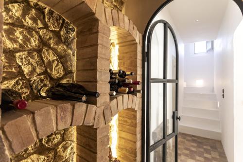 Habitación con pared de piedra y puerta con botellas de vino. en Casa Berne - Deia, en Deià