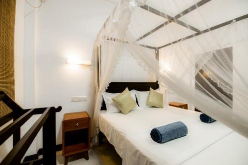a bedroom with a white bed with a canopy at Sea Yo Villa - Hikkaduwa in Hikkaduwa