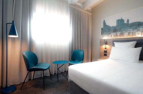 a hotel room with a bed and two chairs at Mercure Bergamo Centro Palazzo Dolci in Bergamo