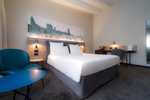 a bedroom with a large white bed and a blue chair at Mercure Bergamo Centro Palazzo Dolci in Bergamo