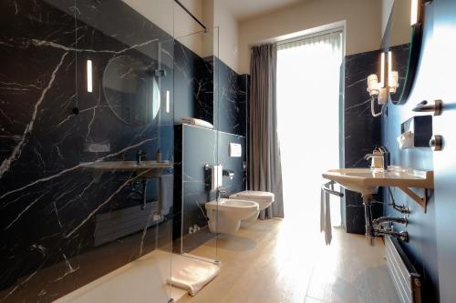 a bathroom with a toilet and two sinks and a shower at Mercure Bergamo Centro Palazzo Dolci in Bergamo