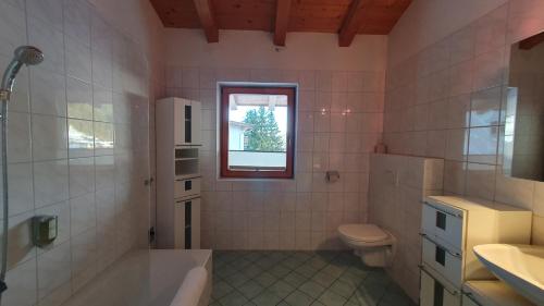 a bathroom with a tub and a toilet and a window at Haus Carina in Kirchberg in Tirol