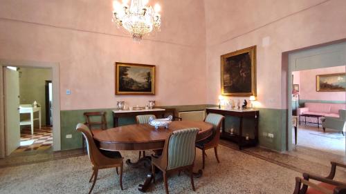 uma sala de jantar com uma mesa e cadeiras e um lustre em Foresteria di Casa Winspeare em Depressa