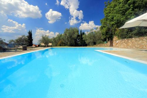 a large blue swimming pool with an umbrella at Castello di Bibbione in San Casciano in Val di Pesa
