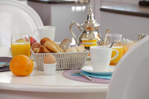 a table with a breakfast of eggs bread and orange juice at The Originals Hôtel Le Cise Restaurant Chambres et Suites in Ault
