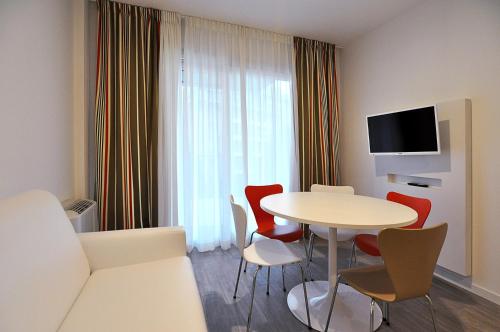 شقق بي بي هوتيلز الفندقية أرسيمبولدي في ميلانو: غرفة مع طاولة وكراسي وتلفزيون