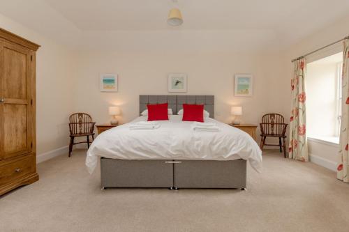 a bedroom with a large bed with red pillows at Pant Farmhouse in Ayr